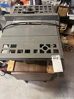 Top view of the Makita table saw showing metal tabletop with grid, power cord, and stand.