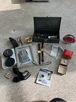 Overview of lot showing various small travel clocks, watches, mini cassette, sunglasses, and metal box with locks and keys