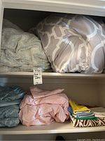 Shelf lower down with folded Ralph Lauren sheet sets in blue and pink, towels and kids washcloths.