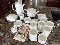 Full set of Rosenthal Variation porcelain coffee and kitchen items arranged on a dark kitchen counter, visible coffee pot, teapot, multiple mugs, creamer, sugar bowls, butter dish, and a small lidded container.