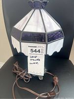 Front view of the stained glass lamp showing white and purple glass panels, brown cord, and metal base