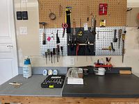 Workbench with mixed hand tools hung on pegboards and some tools arranged on the work surface.