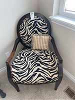 Front view of chair showing zebra patterned upholstery and small beige pillow.
