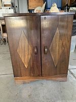 Front view of wooden liquor cabinet showing dual doors with diamond inlay and wooden handles