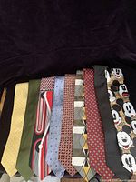 Photo showing all 9 men's ties arranged side-by-side including various colors and patterns.