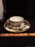 Photo showing the cup, saucer, and dessert plate with a ruler indicating size. The cup is 4 inches across, saucer approximately 5.5 inches.