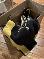 Box containing golf head covers, towels, and Cobra iron covers, mostly black and yellow tinted covers and towels visible.
