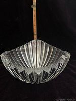 Side view of a faceted clear crystal bowl showing vertical ridges and scalloped edge with measuring stick indicating height.