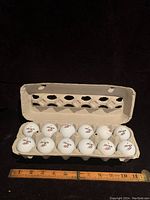 One dozen white Pinnacle golf balls in an egg carton style golf ball holder with a measuring tape at bottom.