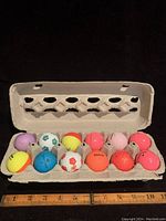 Top view of one dozen golf balls in a cardboard holder showing varied colors and slight use marks.