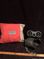 IZOD storage bag alongside Bushnell YardagePro 500 golf distance finder showing front and lenses, with measuring tape for scale.