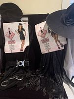 Two female costumes displayed: black witch costume with hat, and police outfit with belt, cap, and handcuffs.