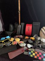 Photo showing multiple pairs of sunglasses, reading glasses, and cases arranged together.