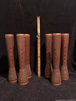 Set of six vintage wooden spools standing upright with measuring stick showing height.