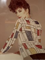 Close-up of the model wearing a long-sleeve blouse with a geometric Mondrian-style pattern of colored blocks separated by black lines.