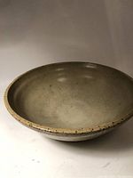 Round earthenware bowl, matte cream speckled finish visible from angled side view