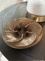 Top-side angled view showing raised petals and textured brass surface of the flower sculpture.