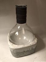 Photo of the glass wine decanter resting inside the rough-textured concrete stone chiller base with white lining inside the base.