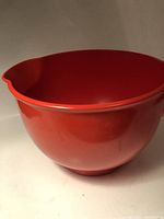 Front and side view of a bright red glossy Dansk mixing bowl showing the pouring spout.