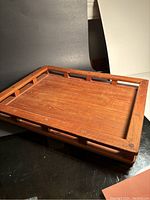 Full view of the rectangular wooden serving tray with rails and open edges, showing wood grain and overall tray shape.