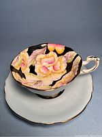 Side view of tea cup on saucer showing exterior pale blue color, scalloped rim, handle with gold trim, and saucer shape