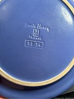 Close-up of the bottom of one plate showing embossed Emile Henry France logo and date code '99 96'.