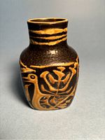 Front view of 4.5 inch tall faience vase with graphic bird design in gold and brown tones.