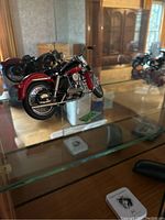Detailed close-up of a red Harley Davidson miniature motorcycle model inside a glass cabinet.