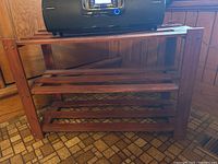 Front view of the wooden stained slatted shelf with items on top showing construction details.