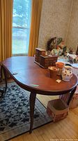 Full view of wooden dining table surface with items on top, missing leaf section