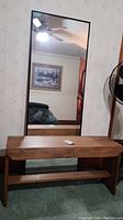 Full view of the wood bench with the large mirror behind it, showing the natural wood finish, black trim on the mirror, and overall size proportions.