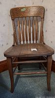 Front view of vintage solid wood chair showing vertical slats and cracked seat.