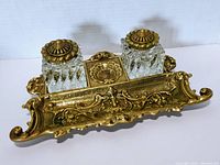 Top and angled view of the antique ink well set showing two crystal ink bottles with brass lids on an ornate brass tray