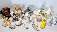 Full view of nineteen assorted figurines on white background showing variety including animals, children, shoes, and floral vases.