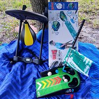 Photo showing the battery operated speed punching bag with a black and yellow bag suspended on a frame with digital timer base, beside a child's golf set including a putter, balls, and putting game board.