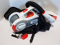 Photo of Black & Decker Auto Pivot handheld vacuum, flexible hose, several attachments, cigarette lighter power adapter, and black storage bag, all on white background