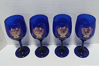 Four cobalt blue wine glasses with Harley-Davidson motorcycle emblems, standing upright showing front detail.