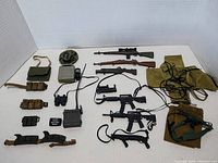 Full view of all vintage GI Joe toy weapons and gear laid out against white background