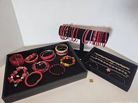 Photo showing various red bracelets and bangles, some on display stand and others loose in a box