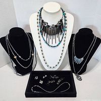 Full display of all hematite jewelry pieces including necklaces on mannequins and smaller pieces in a black display tray on table