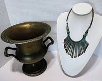 Photo showing vintage brass ice bucket and patina tribal fringe necklace on display stand