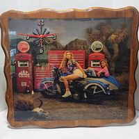 Front view of clock showing full image with two women on motorcycle, Mac Tools toolbox and gasoline pumps, and clock hands at 12:45:31 approximately.