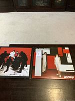 Photo showing two LP record albums side by side on a table. Left album is White Blood Cells with band members and shadows; right album is De Stijl with band members in white on geometric background.
