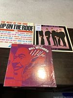 Photo of three sealed LP records: The Drifters album, Bill Withers album, and The Zombies album.