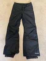 Full front view of black women's ski pants with Columbia branding on left lower leg.