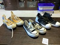 All four pairs of shoes shown together on dark table with MaxSold lot card 212.
