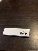 Closed white rectangular presentation box with 'Dokdo Beautiful Island of Korea' branding on top, on a dark wood surface.