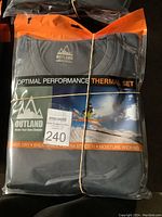 Two packs of Outland Optimal Performance Thermal Sets in original packaging showing front packaging with brand, size L, and features.