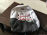 Vans NASA Space Voyager themed backpack laying on table, white and black with red bungees and front NASA print