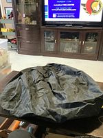 Folded black tire cover on table with TV and furniture in background